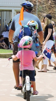 One Big and Two Small Boys Fly Flags As They Pedal Along Beachfront-gallery